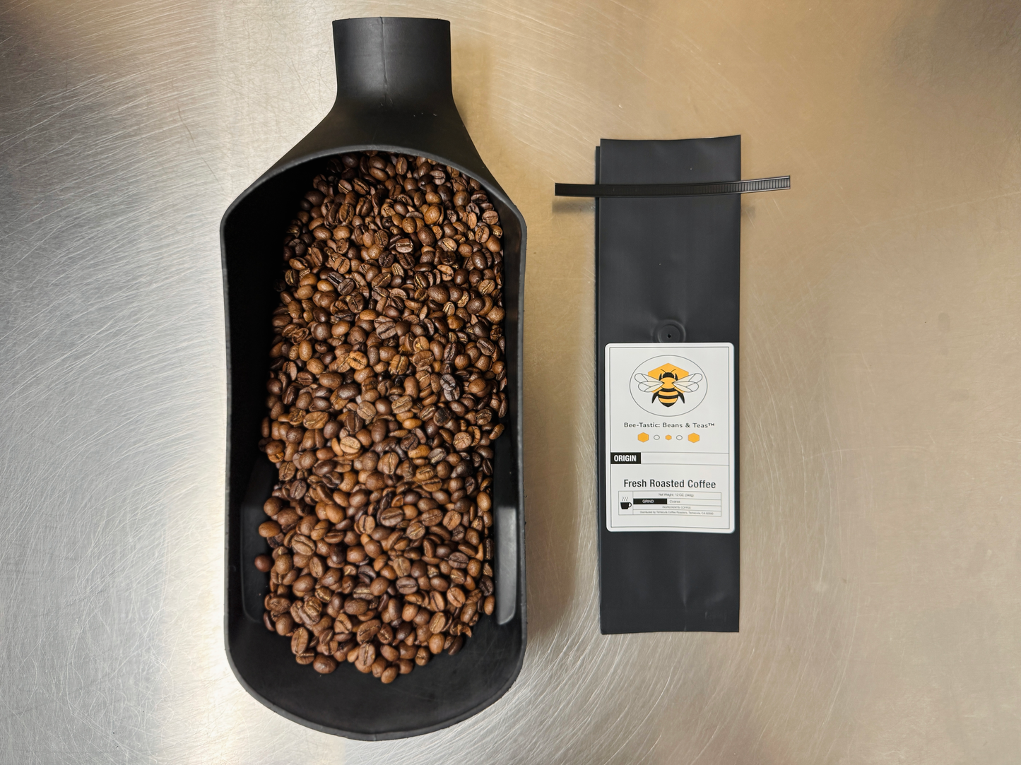 Bee-Tastic: Beans & Teas™ bag sitting next to a scoop of freshly roasted coffee beans.
